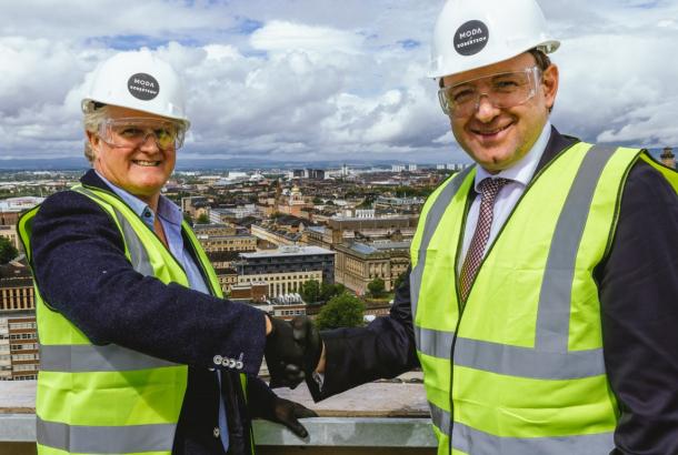Tony Brooks, Managing Director at Moda Living and Elliot Robertson, Chief Executive, Robertson Group, both dressed in PPE, shaking hands.