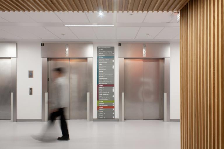 NHS staff member walking through a corridor next to lifts in the Freeman Hospital, Newcastle, where Robertson Construction North East delivered a strategic refurbishment for the Trust