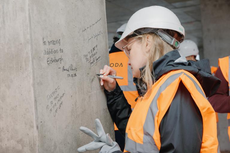 Person signing a pillar at a construction topping out