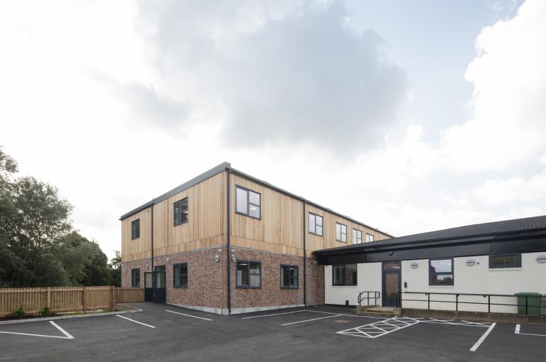 The outside of Broadwalk PRU Pupil Referral Unit in Salford, showing the playground, extension and original building.