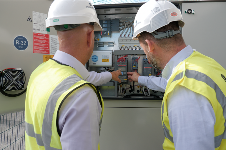 Image of two construction workers checking an electric meter to monitor decarbonisation and energy use