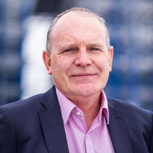 Robertson's Business Development Director, David Mackenzie, wearing a dark blue suit and pink shirt, looking at the camera and smiling.