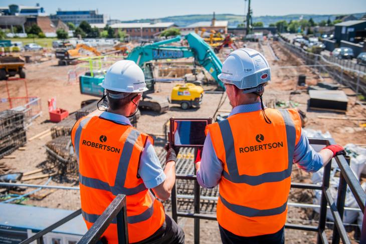 Two people wearing PPE looking across a construction site