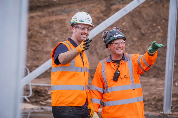 Two members of Robertson Civil Engineering, wearing PPE and pointing.