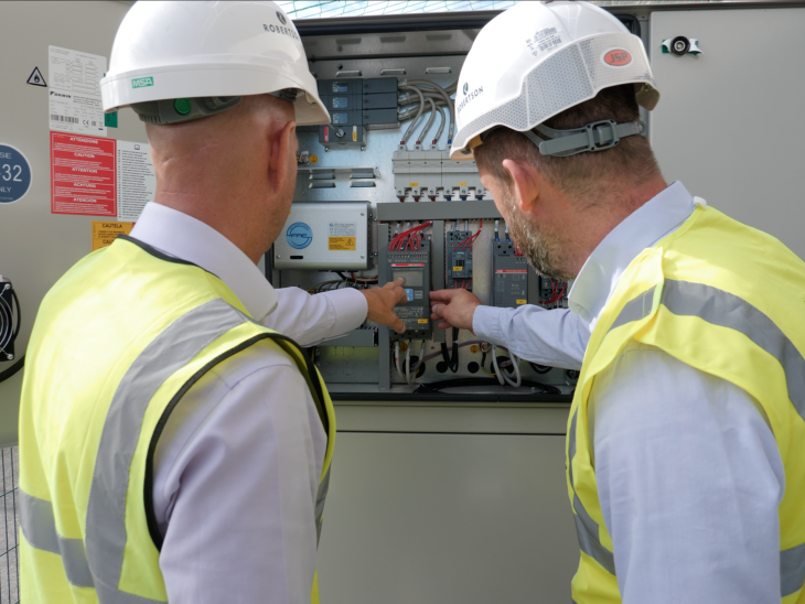 Image of two construction workers checking an electric meter to monitor decarbonisation and energy use