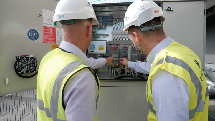 Image of two construction workers checking an electric meter to monitor decarbonisation and energy use