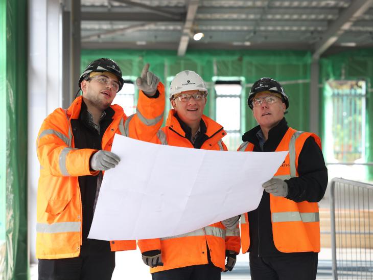 Three construction team members looking at a drawing and pointing.