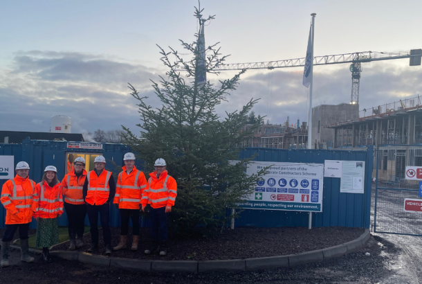 Robertson Construction Tayside site team at Perth High School standing in front of a Christmas tree and Perth High School where a new school is being constructed