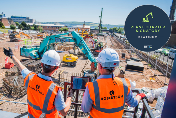 People in personal protective equipment looking out to a construction site containing plant machinery and stored materials