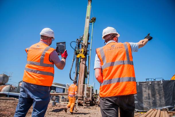 Two Robertson employees looking out onto a construction site photographing construction activity