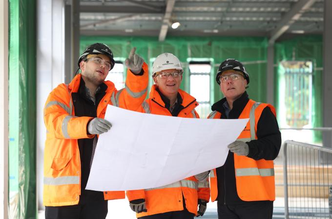 Three construction team members looking at a drawing and pointing.