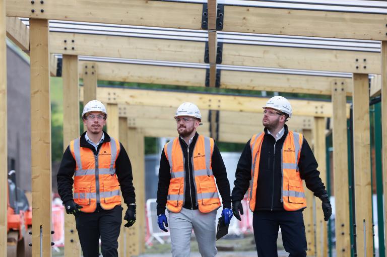 Three members of Robertson's site team walking towards the camera, discussing the project.