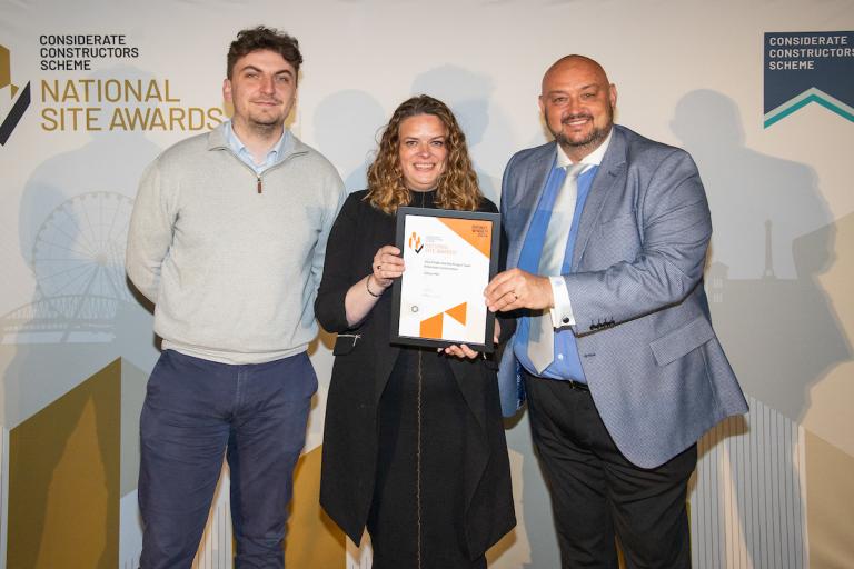 Three people holding an award certificate
