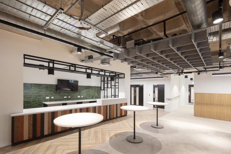 Interior of an office building showing tables and a communal kitchen/leisure area