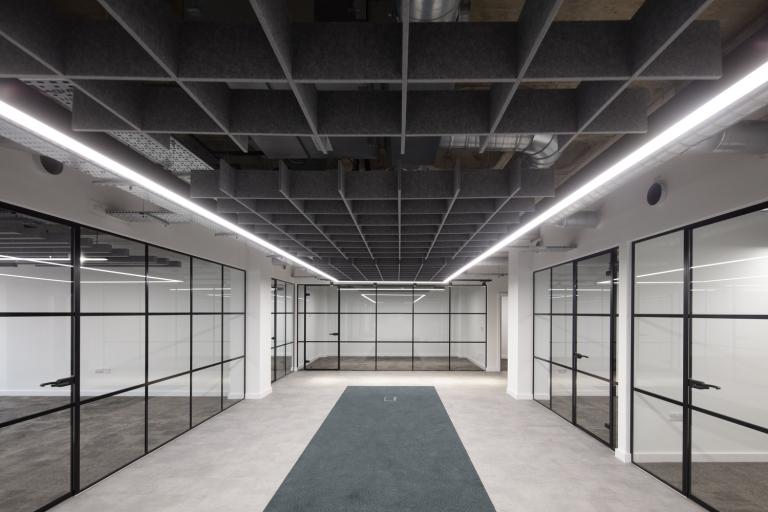 Interior of an office building hallway with clear glass rooms either side