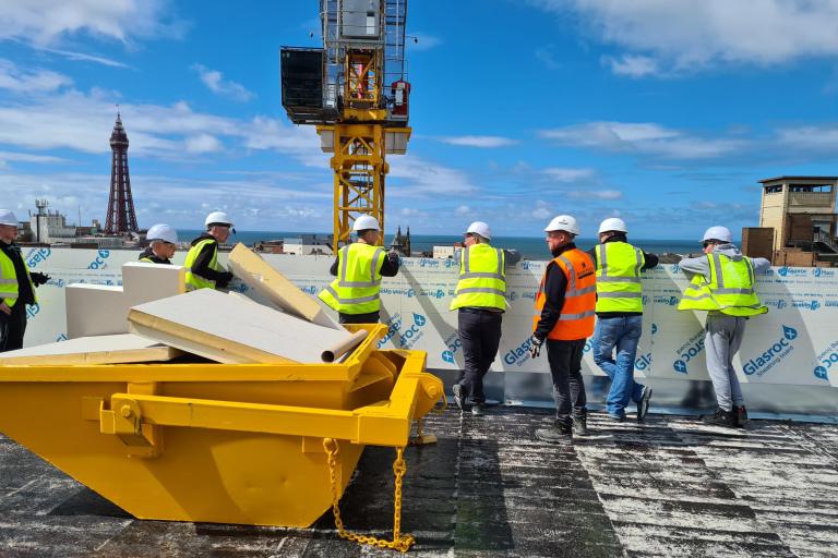 Students in PPE on the roof of a building that is being constructed looking out onto Blackpool Tower