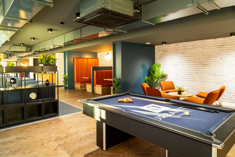 Pool table within a well-lit modern student accommodation surrounded by communal seating