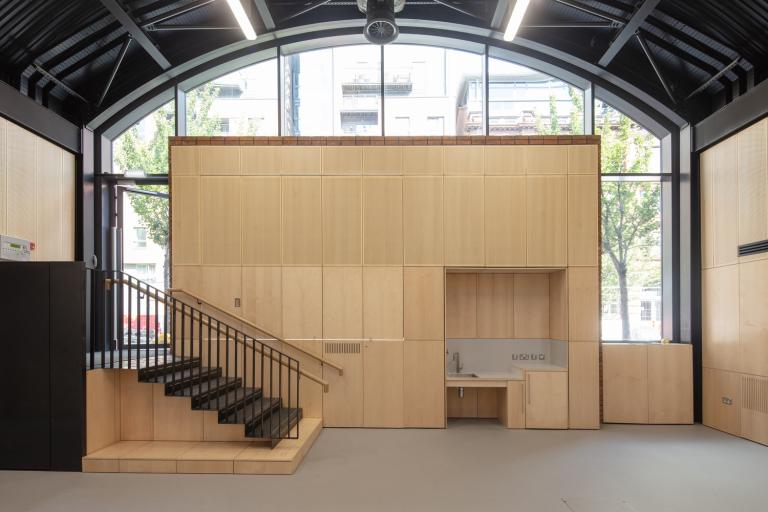 Contemporary space for arts activities within the new HOME Arches, showing stairs leading out to the street and a large built-in wooden storage cabinet