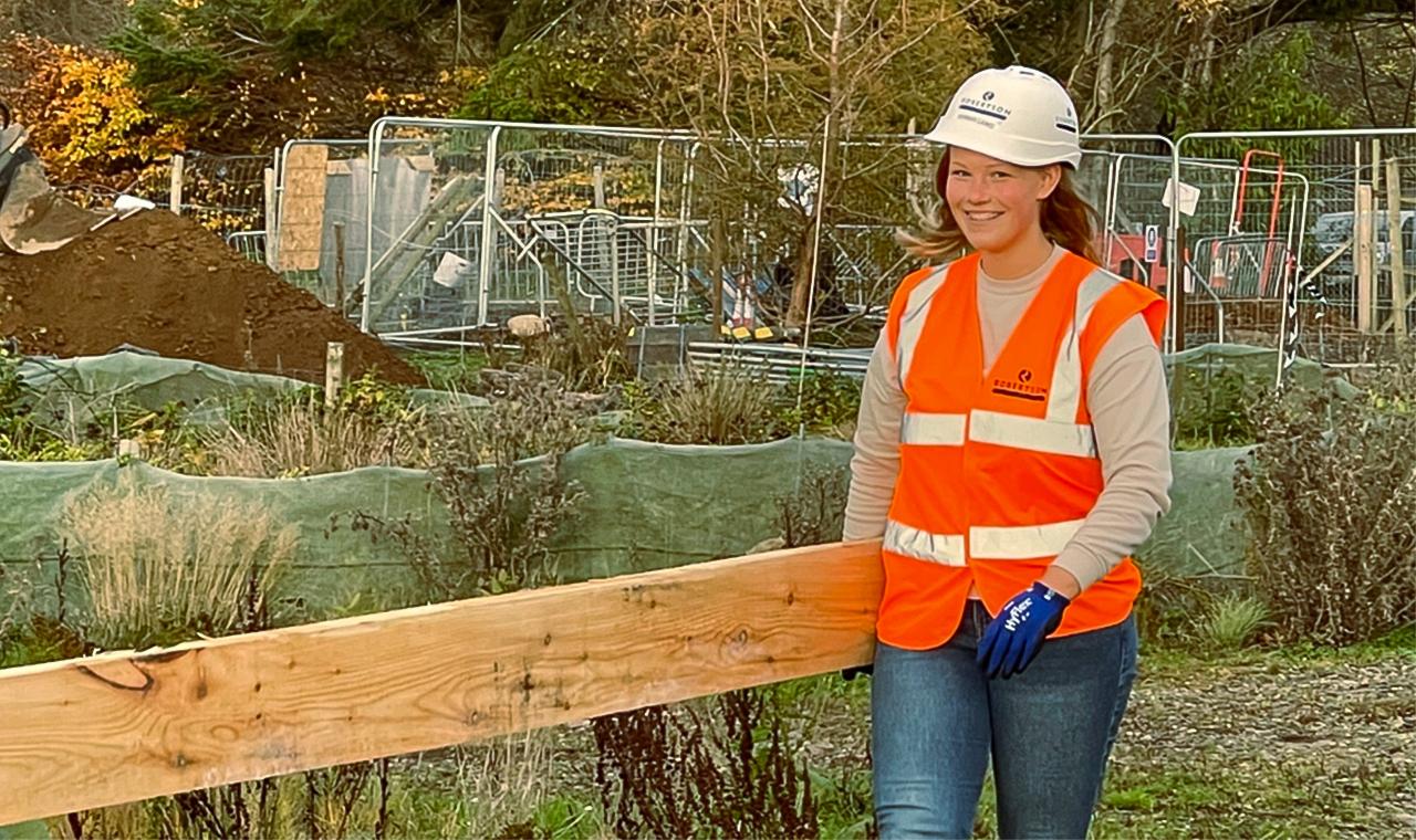 Woman in PPE carrying plank