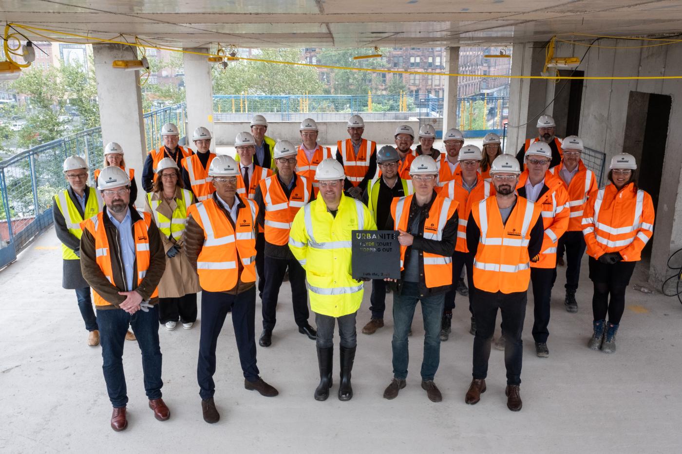 Lots of people standing on the fourth floor of an in-progress construction site 