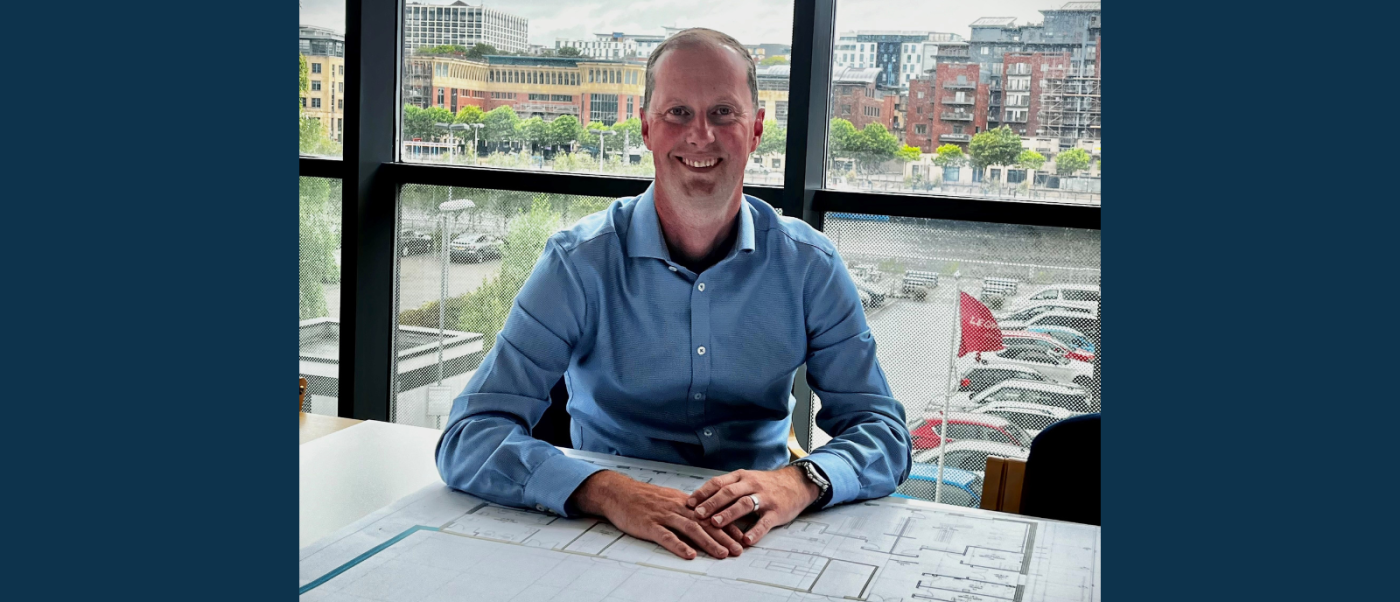 New Managing Director of Robertson Construction North East sat behind construction plans in front of a glass window